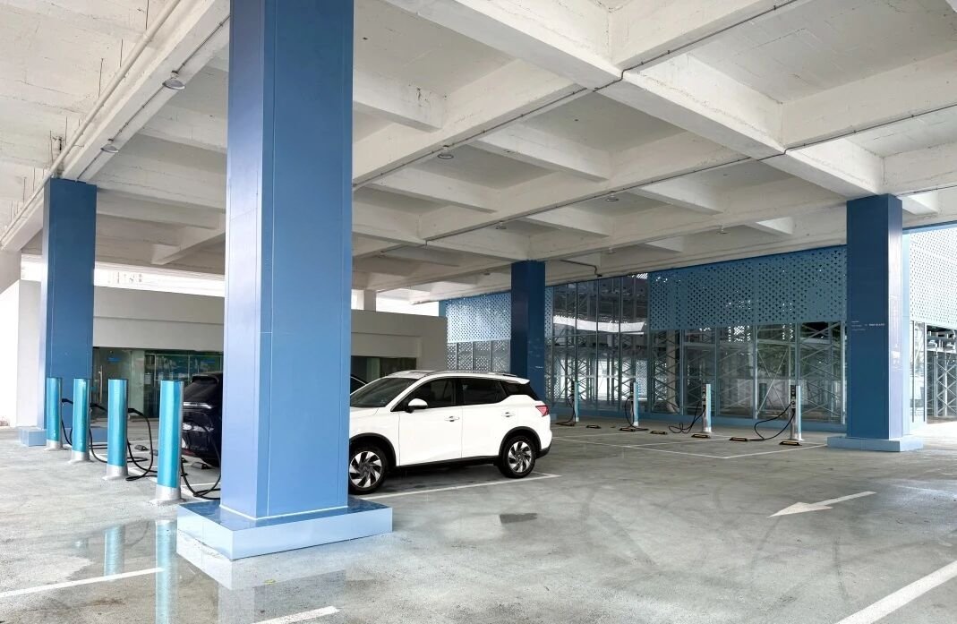 Covered EV fleet charging depot with multiple charging bays and vehicles plugged in, showing large-scale depot electrification