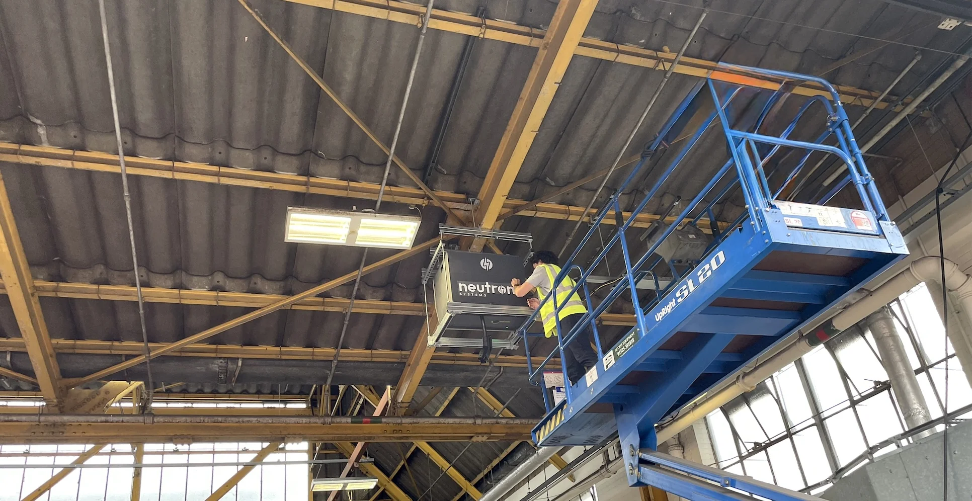 Neutron NSNF0014DDC drop-down overhead EV charger extended from ceiling mount in bus depot