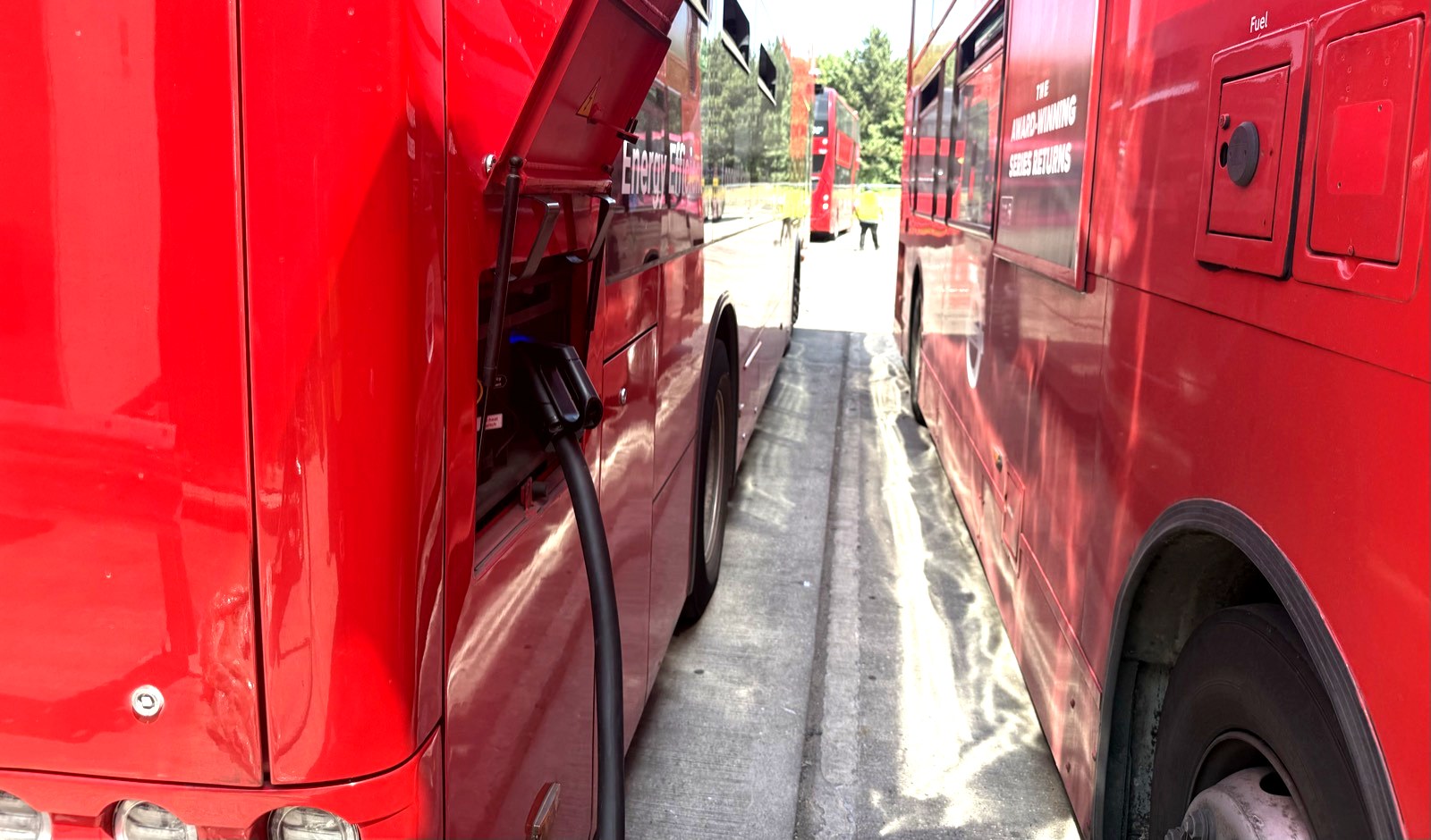 London electric buses with charging cable connected at a UK depot
