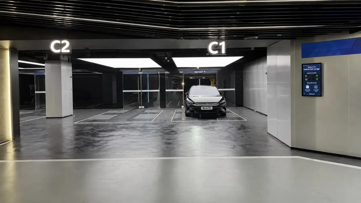 Vehicle entering an automated StackCharge parking bay, with live bay availability shown on a display