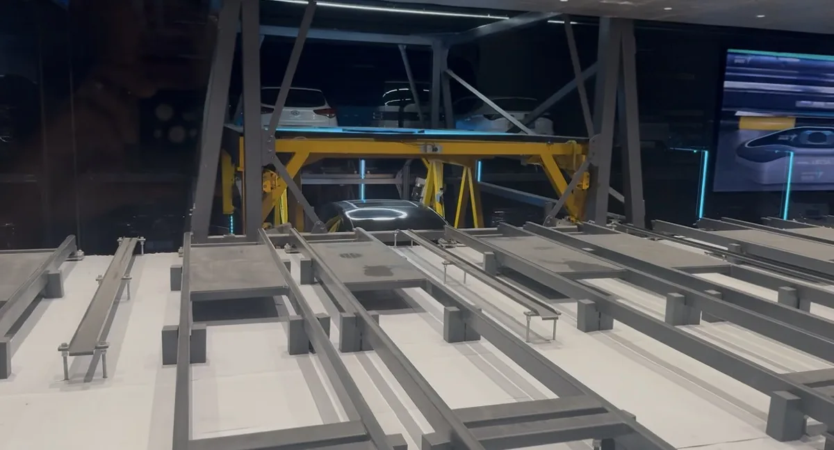 Chain transfer unit lifting a vehicle onto a StackCharge stacking frame on rails